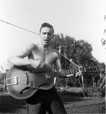 Young man playing guitar outdoors, 1952