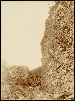 Construction of road through mountain, men cutting/moving stone