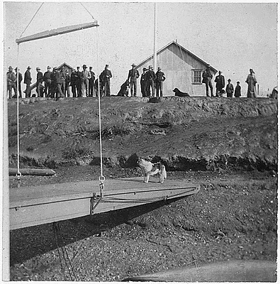 Dog on platform, men on bluff.