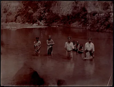 Young women and children, possibly of African decent, bathing/standing in a river