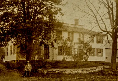 Dr. John H. Hero sitting in front of the Nathan Fisher House