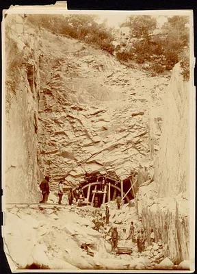 Construction of tunnel through mountain, men standing on rail tracks