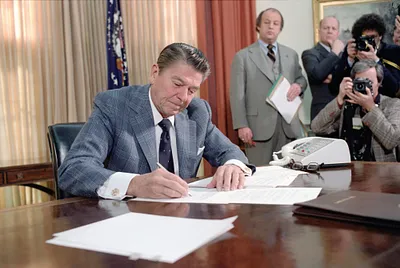 President  Ronald Reagan signing Executive Order on Reductions in Government Spending with James Brady and press in Oval Office