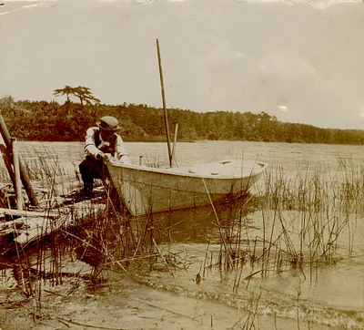 Man pulling boat by dock, Long Pond, South Yarmouth, Mass.