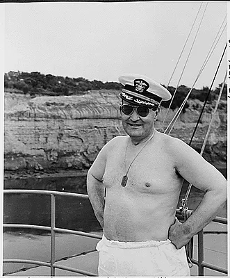 Photograph of President Truman's Military Aide, General Harry Vaughan, wearing the Naval Aide's cap as a joke during the President's vacation cruise to Rhode Island and Bermuda