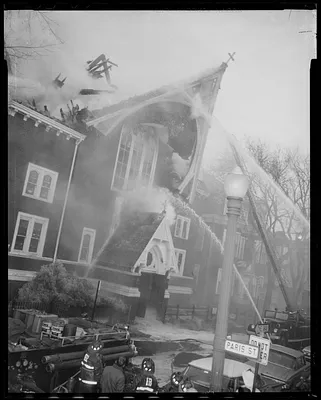 Fire truck hoses spraying water on Sacred Heart Church at the corner of Paris St. and Brooks St.