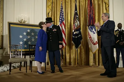 President George W. Bush Applauds as Medal of Honor Recipient U.S. Army Major Bruce P. Crandall Kisses His Wife, Arlene, in the East Room of the White House
