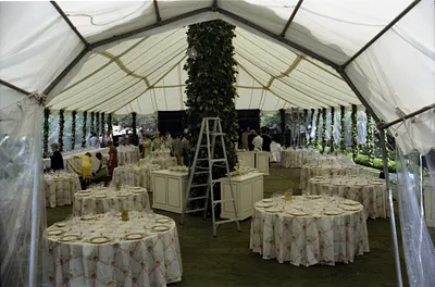 White House Staff Setting Up Tables and Decorations in a Tent on the South Lawn of the White House in Preparation for a State Dinner Honoring Queen Elizabeth II and Prince Philip of Great Britain