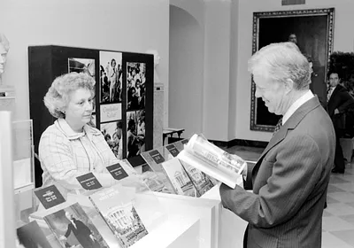 Jimmy Carter at White House Visitors Desk Looking at Guide Books