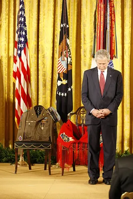 President George W. Bush Bows His Head During a Prayer in the East Room of the White House, Standing Before Two Chairs in Honor of U.S. Army MSG Woodrow Wilson Keeble and His Wife, Bloosom