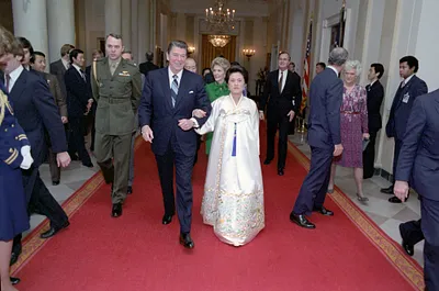 President Ronald Reagan walking with Soon Ja Lee, wife of President Chun Doo Hwan of South Korea with Nancy Reagan, George Bush and Barbara Bush in the Cross Hall