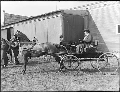 Miss Alice Sargent in Larz Anderson horse and buggy, Miss Dorothy Forbes looks on, Brookline Riding School
