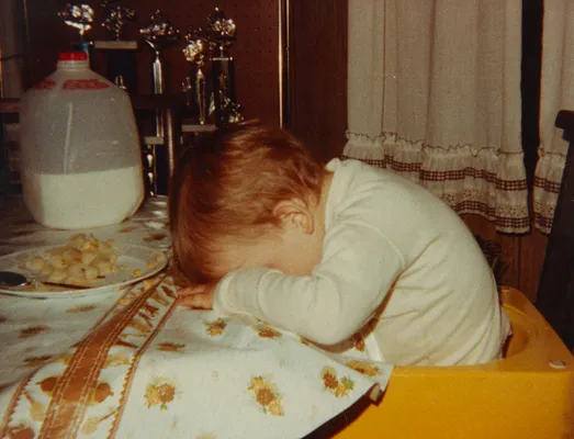Adam George, age 1, falls asleep at the table after too much milk, 1980