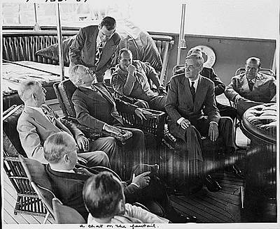 Photograph of President Truman on the fantail of his yacht, the U.S.S. WILLIAMSBURG, chatting with members of his official party on the first day of his vacation cruise to Bermuda: (seated, left to right) unidentified man; Treasury Secretary John Snyder; Theodore Marks, a friend of the President; the President; General Harry Vaughan, Military Aide to the President; Press Secretary Charles Ross; Clark Clifford, Special Counsel to the President (mostly obscured); George Allen, Director of the Reconstruction Finance Corporation