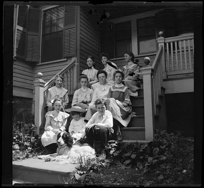 Agnes E. O'Connor, in black bow tie, and group of students on steps of South End Industrial School, Roxbury