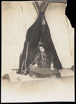 Seated woman dressed as an Indian smoking a pipe