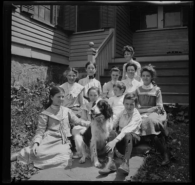 Agnes E. O'Connor, in black bow tie, and group of students on steps of South End Industrial School, Roxbury