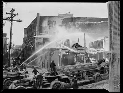 Firefighters using hoses from engines to put out a building fire