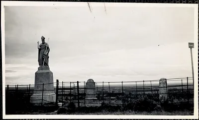 Part of a graveyard with two gravestones and a tall statue