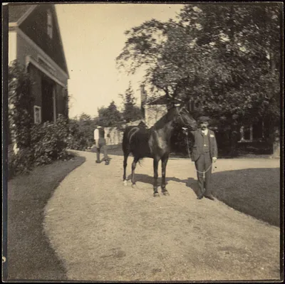 Man with horse in front of barn